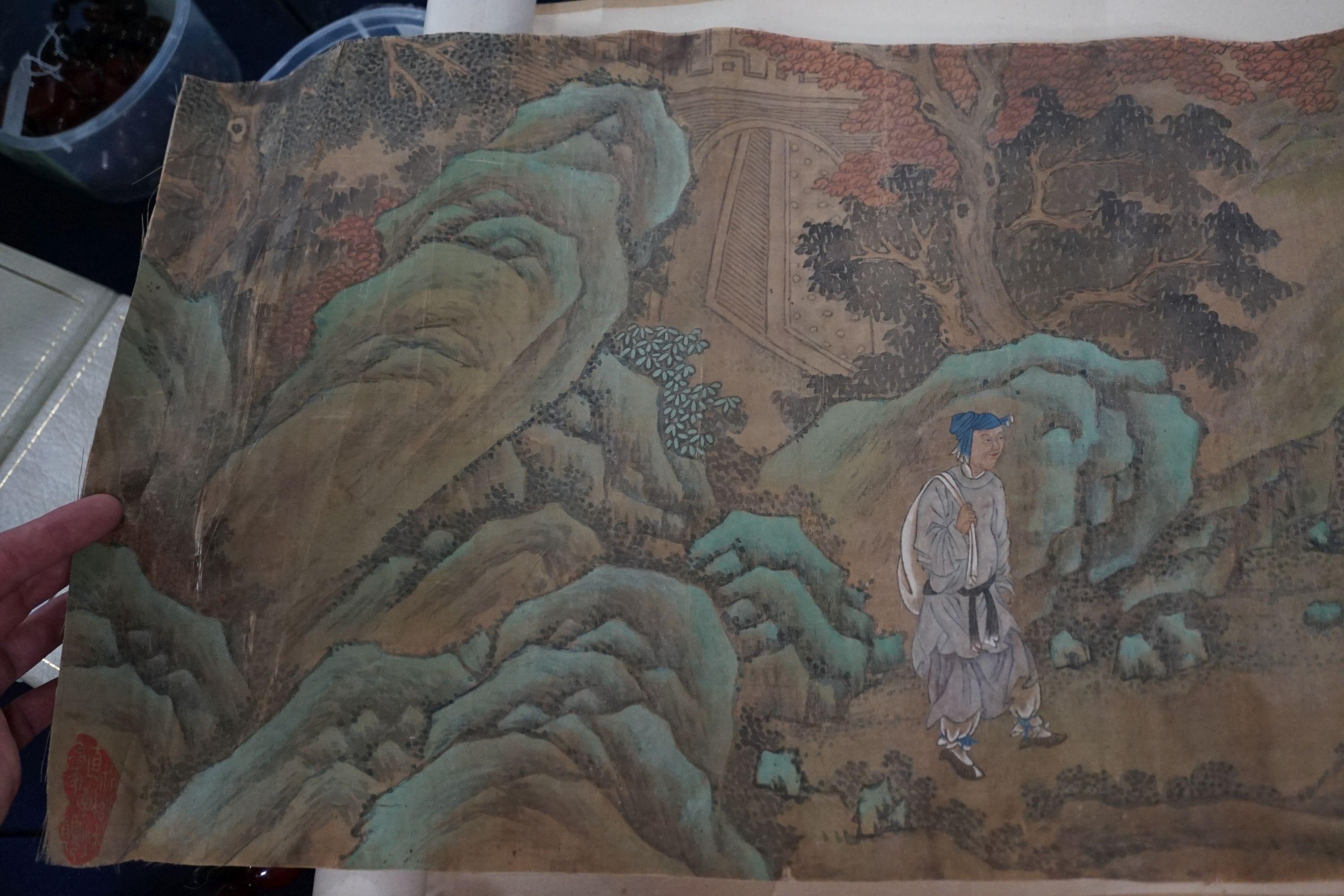 A 19th century Chinese hand scroll painting on silk of figures in a landscape, approximately 206 cm X 32.5 cm